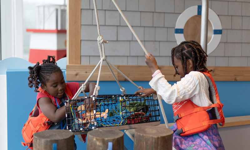 Kids playing with fake lobster trap; Photo Credit: Hannah Ellsworth